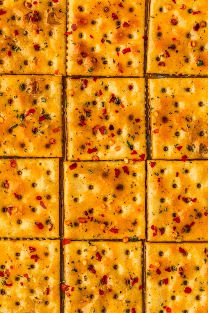 Rows of unbaked seasoned saltines with hot honey.