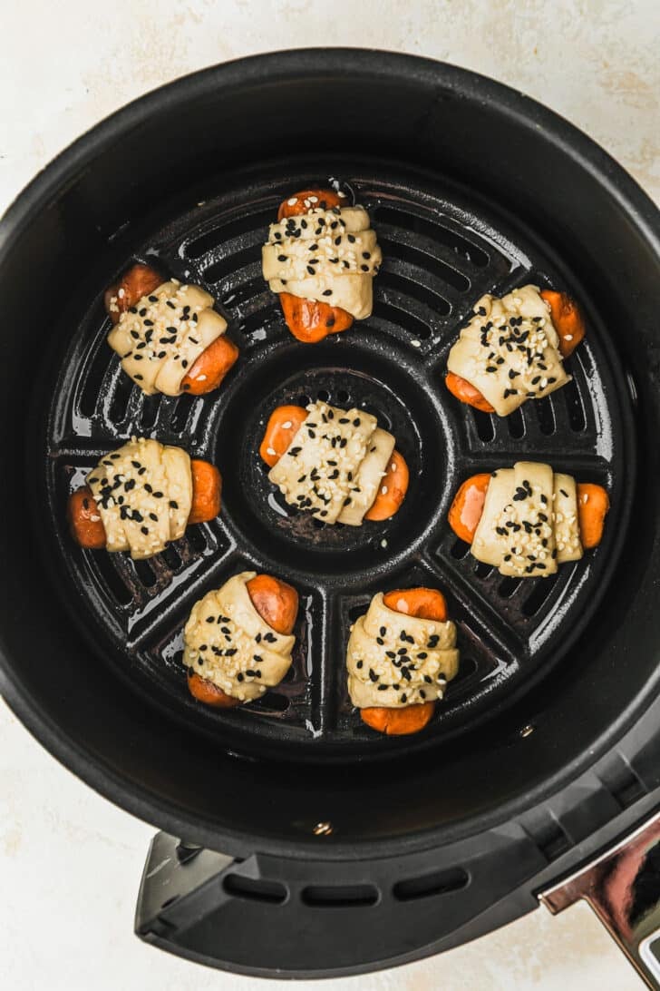 Raw pigs in a blanket in an air fryer.