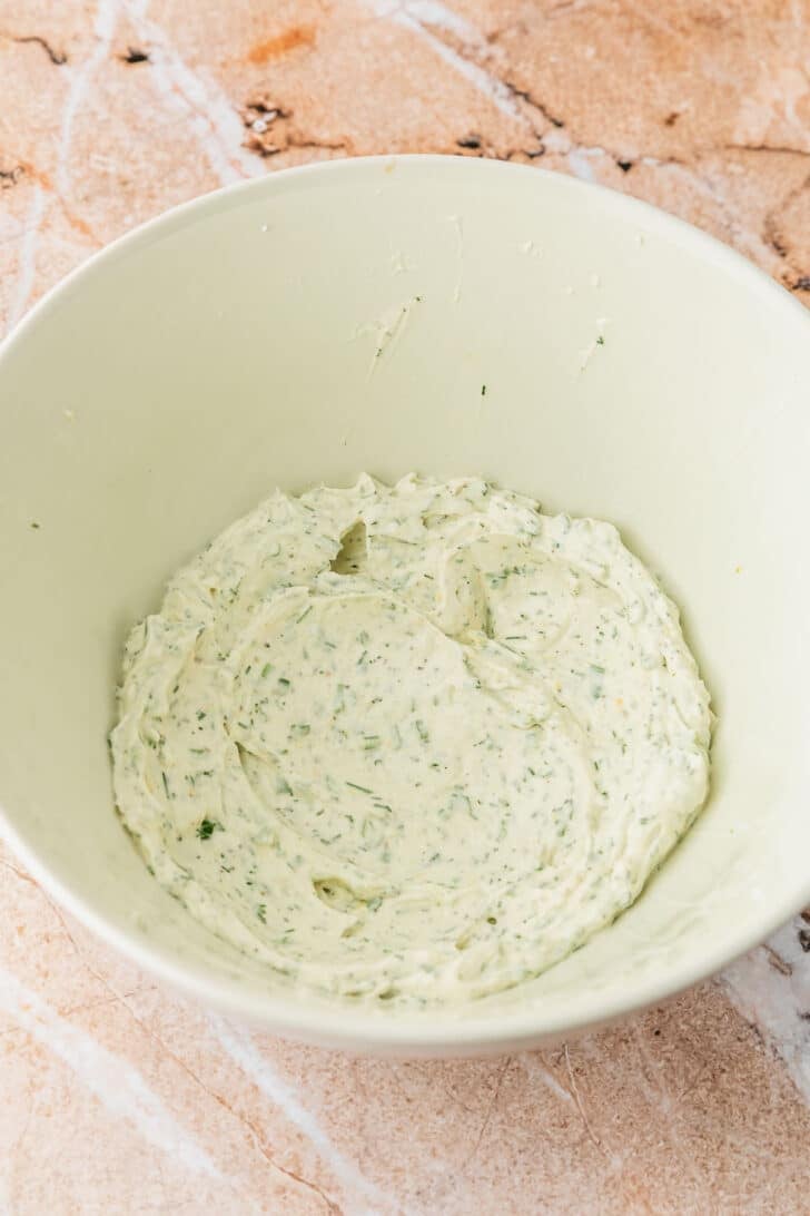 A white bowl of whipped herb cream cheese.