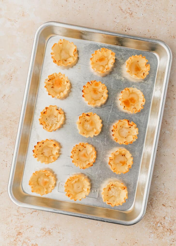 A silver tray of filo shells on a tan marble counter.