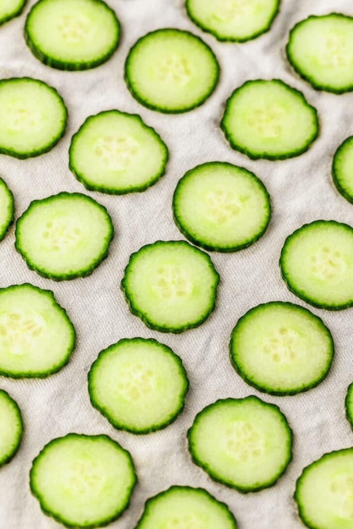 A beige linen with rows of cucumbers.