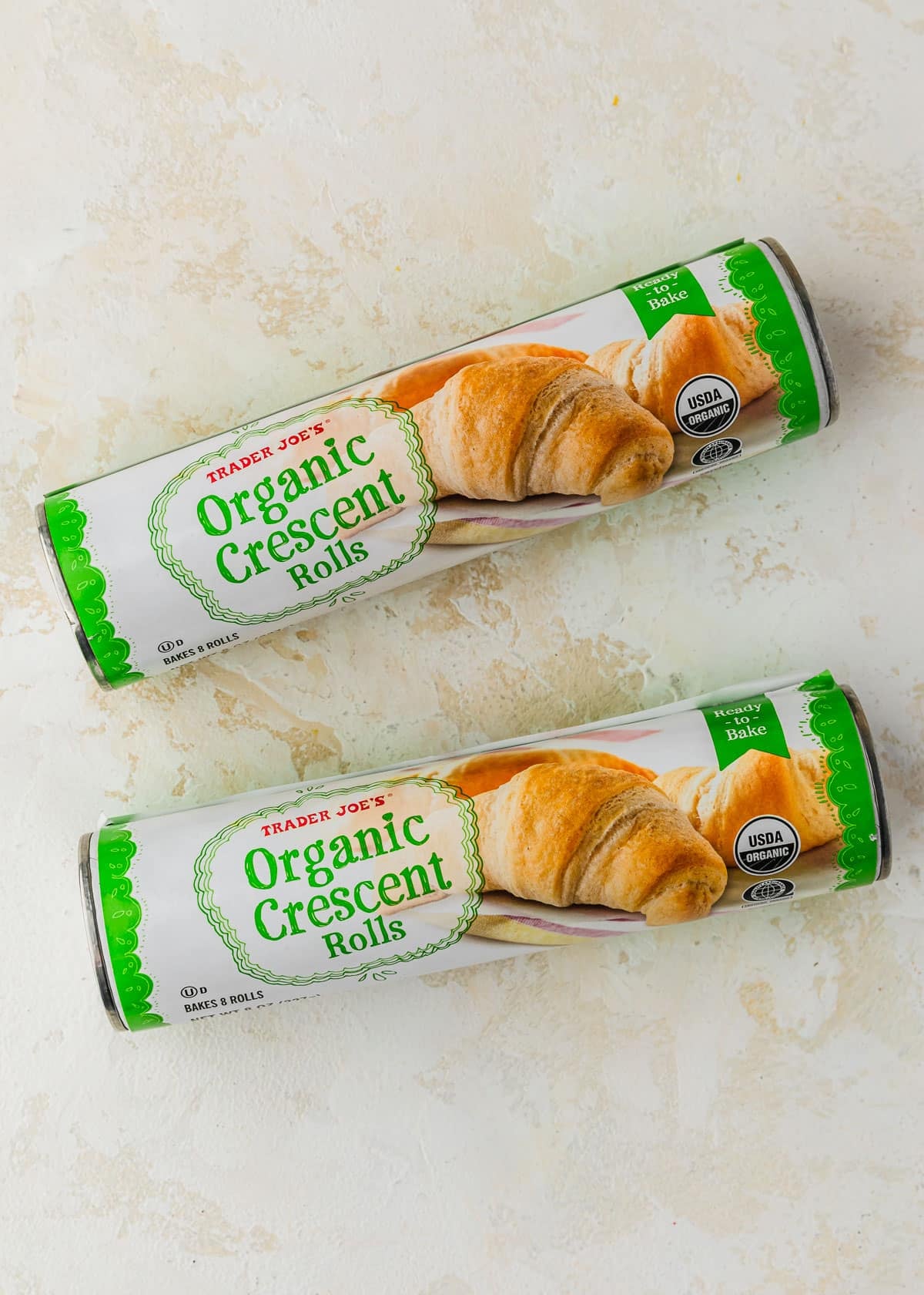 Two rolls of crescent rolls on a beige table.