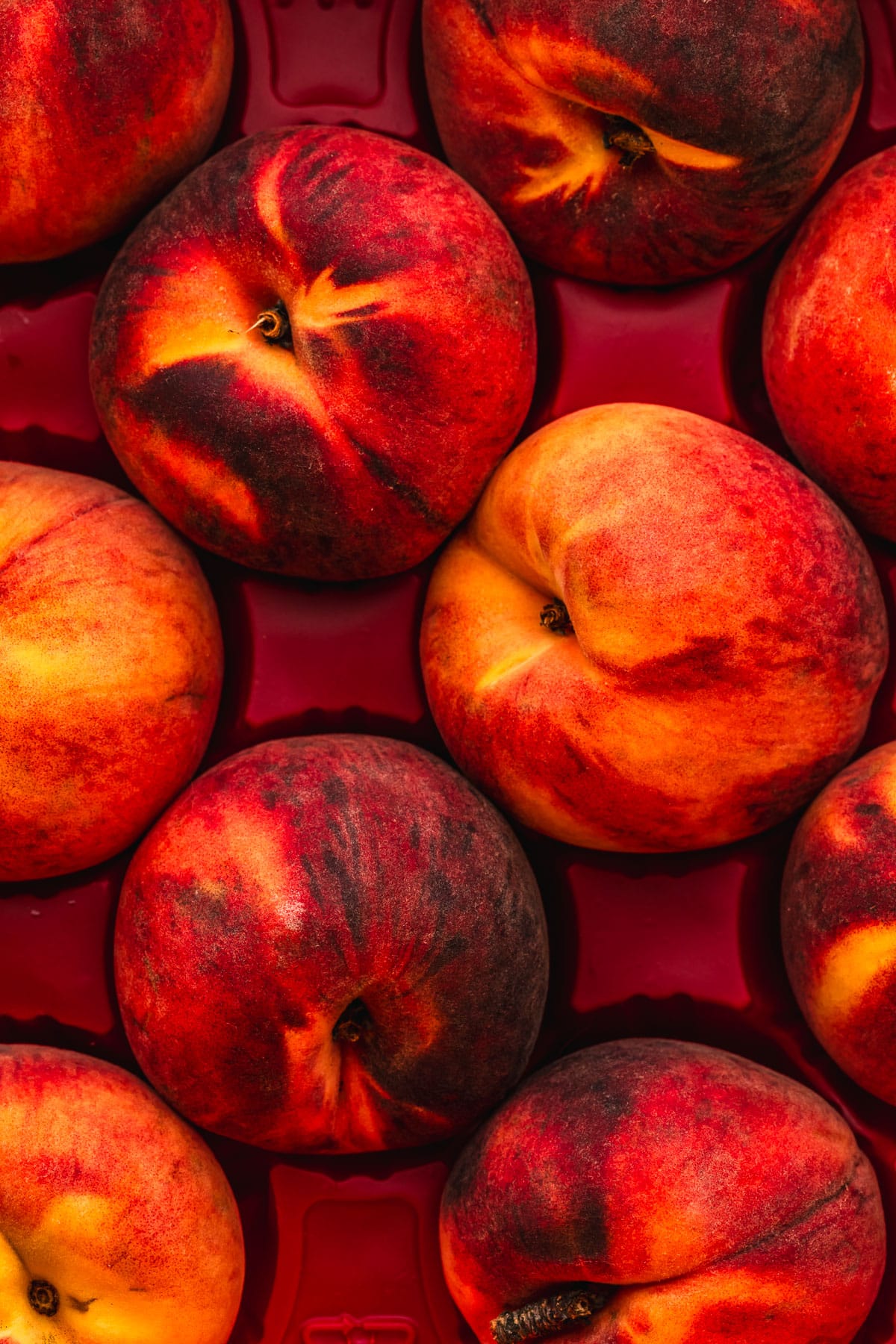 Rows of peaches in a red container.