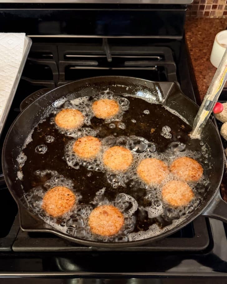 Squash frying in a black pan of oil.