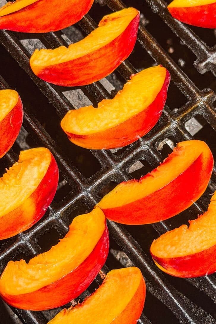 Sliced nectarines on a grill.