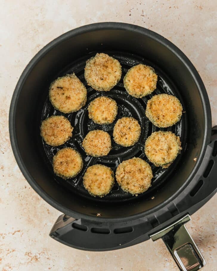 An air fryer with raw fried zucchini.