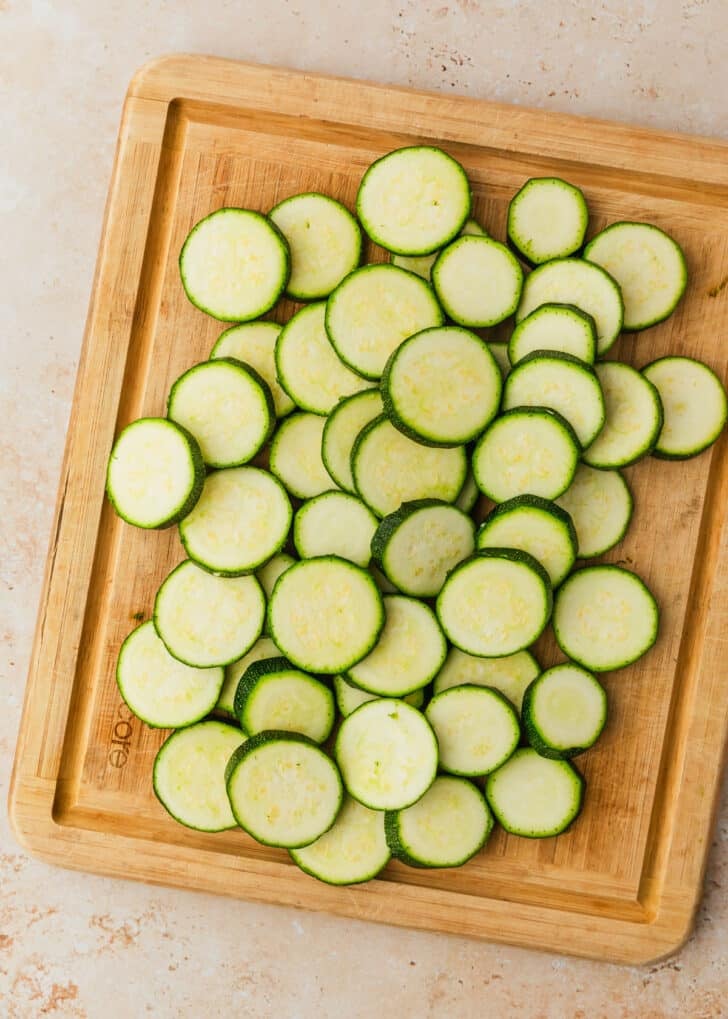 A wooden board of sliced green squash.