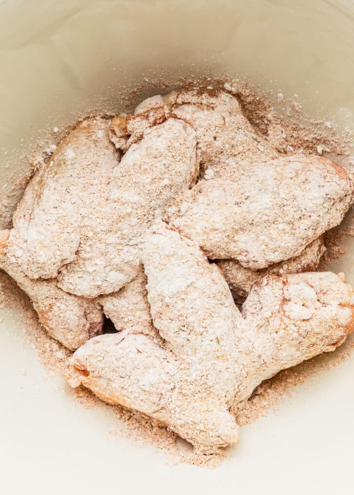 A white bowl of wings, baking powder, and spices.
