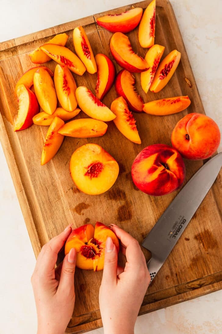 Hands breaking apart a peach.
