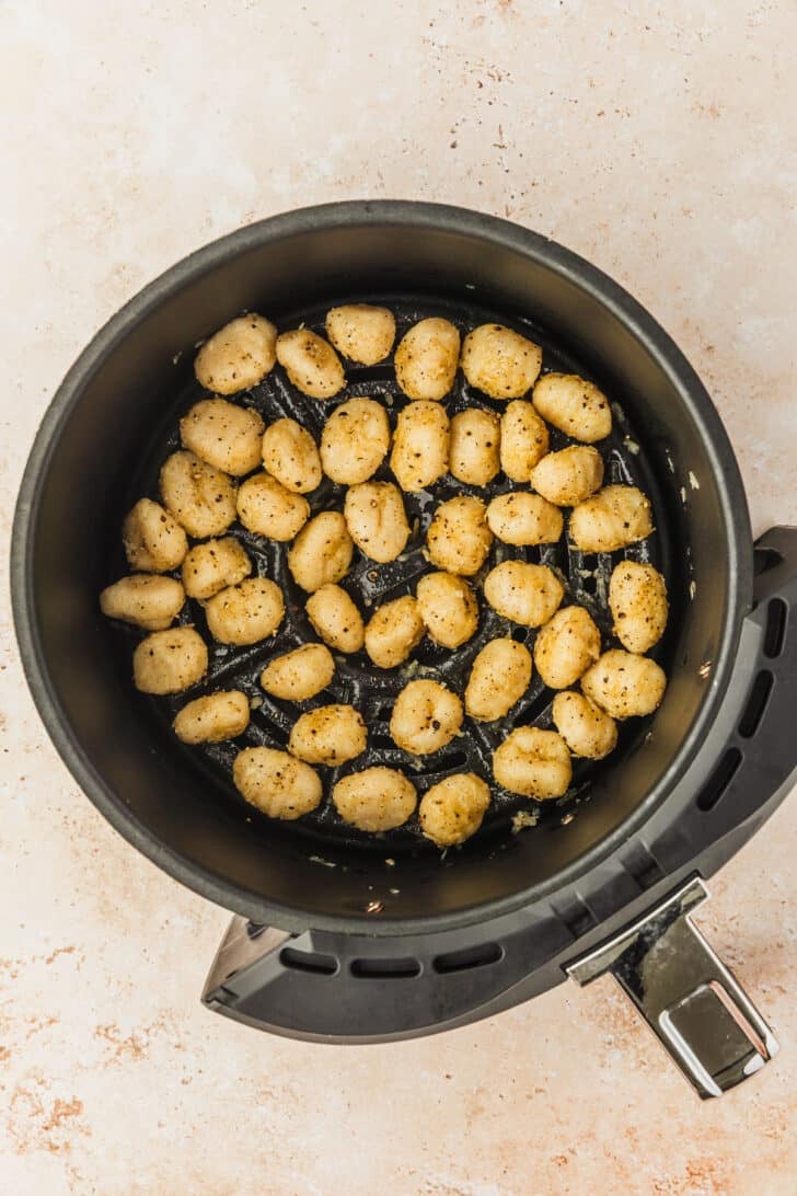 An air fryer basket filled with cacio e pepe gnocchi bites.