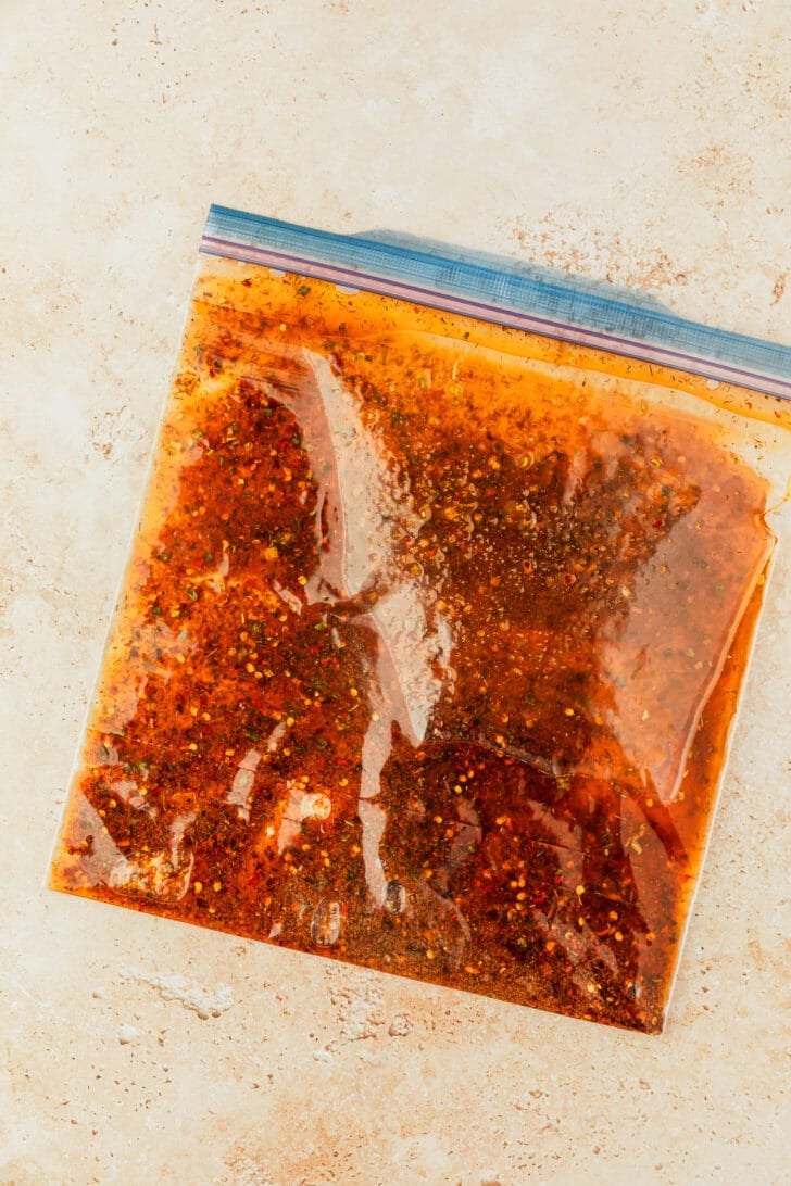 A zipper bag of oil and spices on a tan counter.
