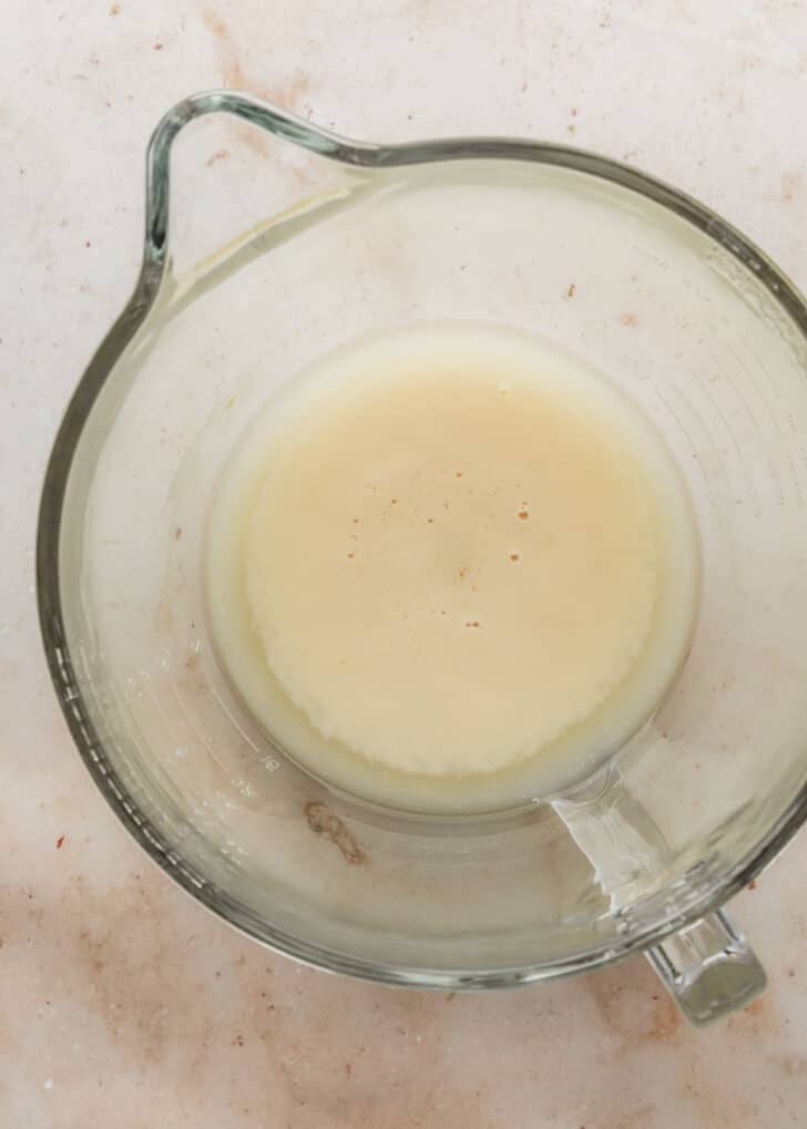 A clear mixing bowl of proofed yeast on a tan counter.