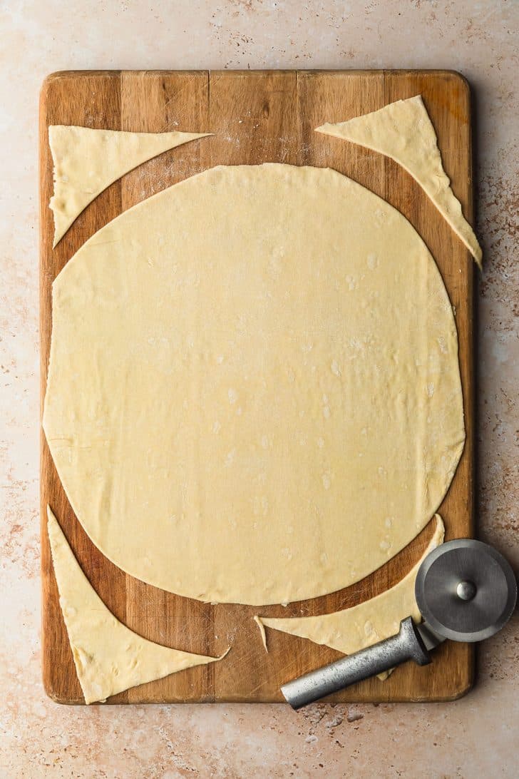 Puff pastry rolled into a circle on a wood board.