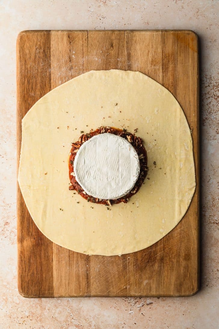 A circle of puff pastry with brie in the center for pumpkin-shaped baked brie.