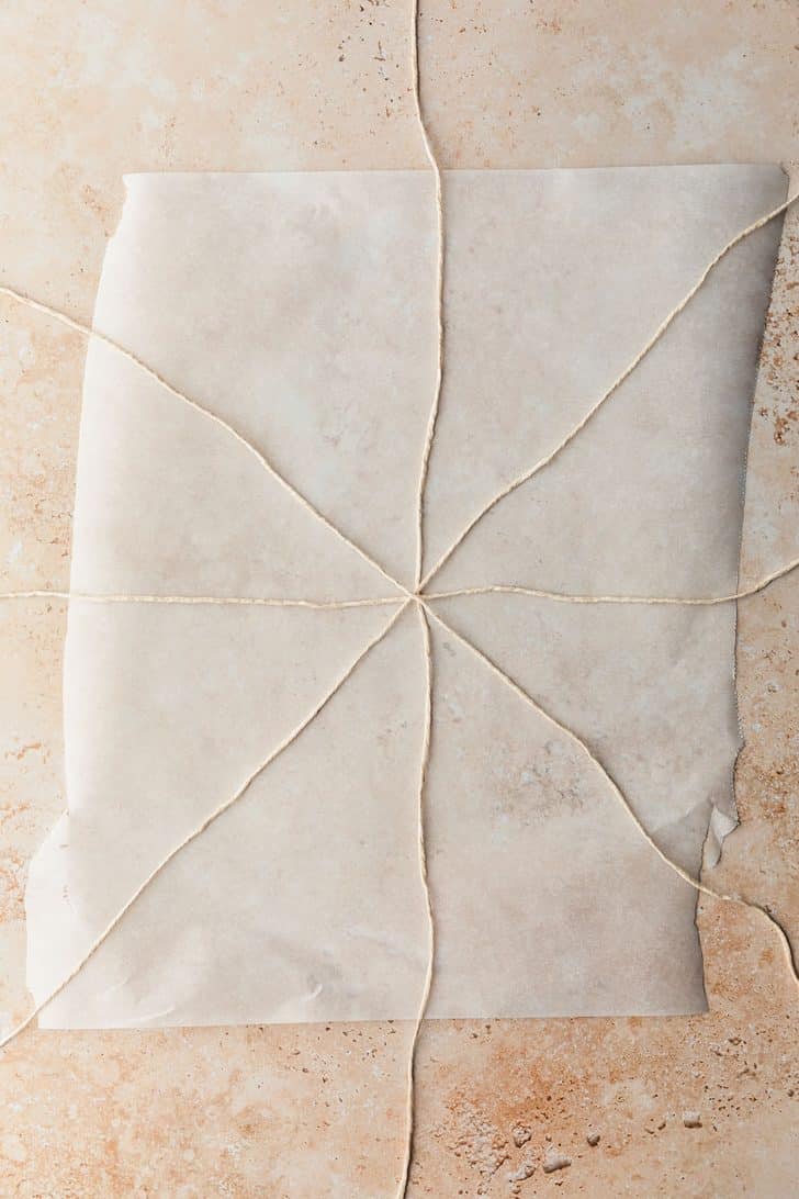 Kitchen twine in a star shape on a piece of parchment paper.
